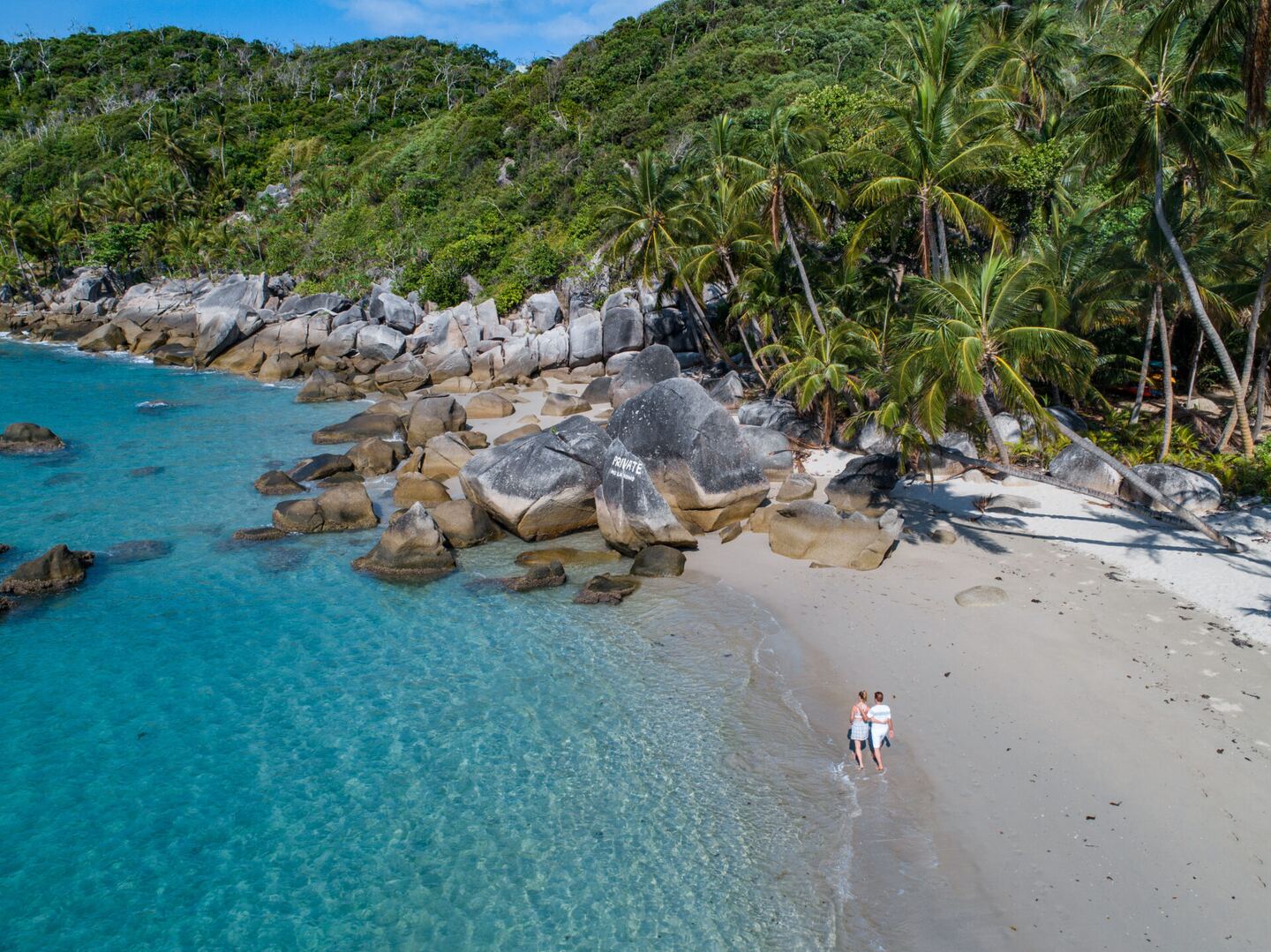 Aerial view along the beach with a guest walking at the water's edge